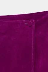 Falda midi de tiro medio tipo pareo confeccionada en piel. Presenta un diseño cruzado con cierre frontal y bajo asimétrico.