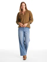 Buzo de punto suave marca Cyrus, color blanco, con cuello solapa y escote en V. Presenta diseño de hombros caídos, mangas 3/4 con puños largos de tejido rib al tono y corte holgado con tajos laterales en el ruedo.