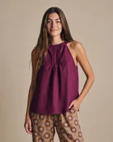 Blusa sin mangas de lino color bordó, con escote halter fruncido, breteles elásticos y diseño acampanado y fluido con pliegues frontales.