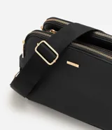 Cartera bandolera Satinato de formato rectangular compacto y textura estructurada, color negro con herrajes dorados. Cuenta con doble compartimento superior con cierre, correa ancha regulable y placa metálica frontal con el logo de la marca.