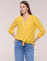 Blusa de calce relajado color amarillo, confeccionada en tela liviana de textura sutil. Presenta escote en V con abotonadura frontal, bolsillo parche en el frente y mangas largas regulables con presilla y botón. Cuenta con ruedo curvo diseñado para anudar en la parte delantera.