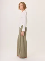 Remera blanca de manga larga con escote en V y detalles de alforzas verticales en el frente y mangas.