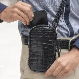 Bandolera porta celular negra de cuero vacuno con textura croco, correa de cinta ajustable y forro interior de tela.