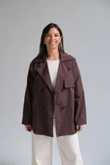 Trench corto color chocolate, con cuello solapa, cierre frontal cruzado con botones y mangas largas.