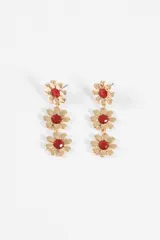 Caravanas colgantes de diseño floral, compuestas por tres flores doradas en cascada con centros de cristal rojo.