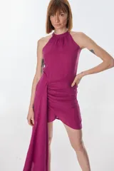Vestido corto color fucsia, con cuello halter fruncido y drapeado asimétrico en la cintura que cae como una cola larga.