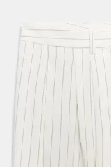 Pantalón wide leg de tiro medio, color blanco con diseño de rayas diplomáticas a contraste, bolsillos laterales y de vivo en la espalda, pinzas en el delantero y cierre frontal con cremallera, botón y ganchos metálicos.