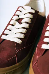 Championes urbanos de gamuza color bordó con suela de goma color caramelo y cordones blancos.