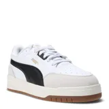 Championes Puma modelo Shuffle Downtown, de diseño urbano con inspiración retro. Presentan una base blanca con detalles en negro, incluyendo la franja lateral característica de la marca, y refuerzos de gamuza en la puntera. Cuentan con suela de goma color caramelo y plantilla SoftFoam+ para mayor confort.