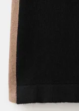 Pantalón de punto negro con diseño recto y holgado, con una franja lateral en tono marrón.