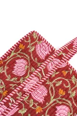 Bolso tipo tote acolchado, con diseño estampado de flores y tallos sobre fondo bordó, y asas con detalles a rayas.