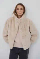 Chaqueta de piel sintética en color burdeos, con cuello alto y cierre frontal oculto. Presenta un diseño de corte recto y mangas largas con puños ligeramente ajustados.