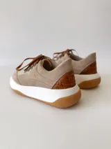 Championes de cuero color visón con cordones marrones, suela blanca y base color caramelo.