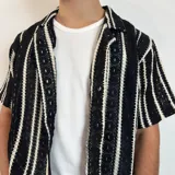 Camisa de crochet color crema con rayas verticales marrones, cuello clásico y corte boxy.