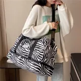 Bolso deportivo de viaje marca Zuomanni, con estampado animal print de leopardo en blanco y negro. Cuenta con doble asa de mano, correa de hombro ajustable y extraíble, y un compartimento inferior independiente con cierre.