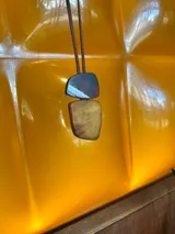 Collar de largo regulable con cordón de cuero y dos piezas colgantes de resina en tonos tierra y marmolados.