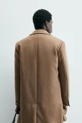 Abrigo de corte regular fit confeccionado en tejido compacto con mezcla de lana. Presenta cuello con solapas de muesca, manga larga, cierre frontal con botonadura y bolsillos de vivo en la cadera. Diseño sin forro interior con abertura central en la espalda.