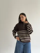 Sweater de punto a rayas horizontales en color marrón y crema, con cuello alto y cierre frontal parcial. Presenta un diseño de manga larga con detalles de hilo brillante en las rayas claras.