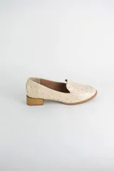 Mocasin de cuero con textura símil avestruz en color suela, con punta redonda y taco bajo cuadrado símil madera.