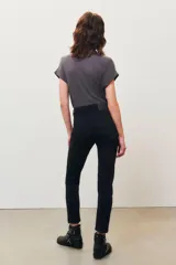 Pantalón de jean negro, corte slim, con tachas metálicas plateadas decorando la abertura de los bolsillos delanteros.