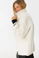 Tapado color crudo con cuello alto, solapas grandes y bolsillos laterales.