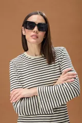 Sweater de punto largo con diseño de rayas horizontales en color negro y beige con hilos de lurex brillantes. Presenta cuello redondo y mangas largas con terminación acampanada.