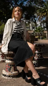 Falda midi de jean color negro, con corte recto y abertura lateral.