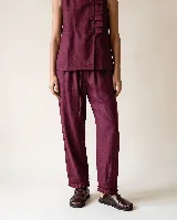 Pantalón de lino color bordó, de silueta relajada y amplia, con cintura elastizada, lazo de ajuste y detalle de pequeños pliegues y ruedo desflecado.