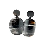 Aros colgantes con forma ovalada, hechos de asta blanca y negra. Se ajustan con clip.