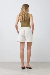 Short color beige claro, de tiro alto, con bolsillos laterales y cierre frontal con botón.