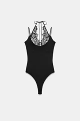 Body negro de tejido elástico con escote redondo y tirantes finos. Presenta un panel superior de encaje floral a tono con diseño halter ajustable mediante lazada en el cuello y cierre inferior con botones a presión.