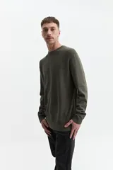 Buzo de punto color beige, con cuello redondo y mangas largas. Tejido con textura piquet y puños acanalados. Corte regular.