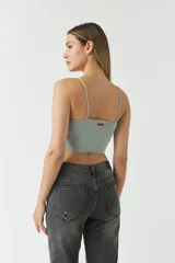 Top de punto color menta con escote en V, tirantes finos y detalle de fruncido central ajustable con cordón. Presenta un diseño corto y entallado.