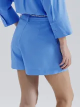 Short de lino en color crudo, de corte recto y tiro medio. Presenta una cintura con pasacintos y un cordón trenzado decorativo con borlas en el frente.