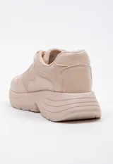 Zapatillas blancas de símil cuero acordonadas con cortes irregulares y pequeños detalles iridiscentes. Su plataforma es irregular y cuenta con 5 cm de alto.