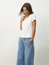 Remera negra de corte clásico con cuello redondo ribeteado con pequeñas perlas blancas.