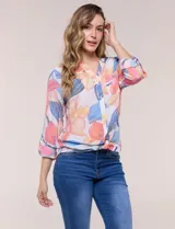 Blusa estampada Zac & Rachel con diseño floral en tonos rosados, azules y amarillos sobre base blanca. Presenta escote en V con botones frontales, mangas tres cuartos con presilla para arremangar y detalle de nudo en el ruedo.