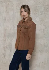 Chaqueta de denim de algodón con corte entallado en la cintura, cuello clásico, cierre frontal con botones metálicos y dos bolsillos con solapa en el pecho.