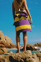 Sweater de hilo de algodón con diseño a rayas horizontales en violeta y amarillo, botones de guampa y bordado con la marca Sierra Mora.