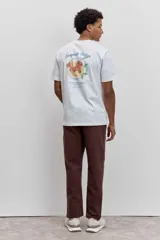 Remera de algodón color marrón chocolate, de corte clásico y cuello redondo, con un pequeño estampado gráfico en el pecho.