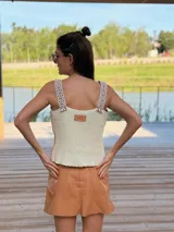 Musculosa marrón de gamuza con bordados blancos en el frente y detalle de flecos en los hombros. Tiene cuello redondo y sisas amplias con terminación de crochet.