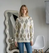 Sweater de punto color crudo con diseño de rombos formados por lentejuelas en tonos dorados y plateados. Presenta cuello redondo, mangas largas y puños acanalados.