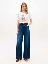 Remera blanca de manga corta Tommy Hilfiger, confeccionada en algodón, con cuello redondo y estampa frontal de un perro golden retriever con suéter a rayas.