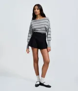 Short de bengalina color negro con cintura estructurada, detalle de botones decorativos y cierre frontal. Presenta un corte evasé que aporta volumen y estructura a la silueta.
