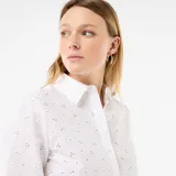 Camisa blanca de manga larga con diseño cropped, cuello camisero, cierre frontal con botones y detalles de bordados all over con perforaciones.