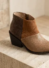 Bota corta de cuero vacuno en color marrón, con diseño de paneles combinados que incluyen textura de reptil en el talón, gamuza en el lateral y cuero liso en la puntera. Presenta un taco cuadrado de 6 cm y suela de caucho antideslizante.