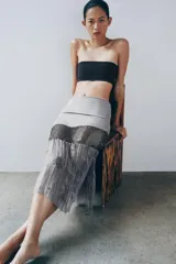 Falda midi de tiro medio, color gris, confeccionada en mezcla de lyocell y viscosa, con detalle de apliques de lentejuelas y bajo de tejido transparente plisado con bordados florales.