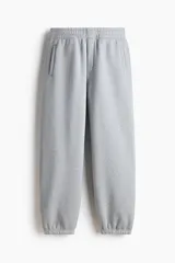 Pantalón deportivo de felpa de mezcla de algodón en color gris melange, con corte relajado, cintura elástica y puños ajustados en los tobillos. Cuenta con bolsillos laterales y cierre decorativo.
