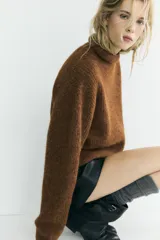 Jersey de punto con textura, cuello subido y manga larga, de corte recto y diseño clásico.