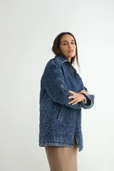Chaqueta de denim azul con diseño acolchado en forma de rombos, cierre frontal con cremallera y bolsillos laterales.